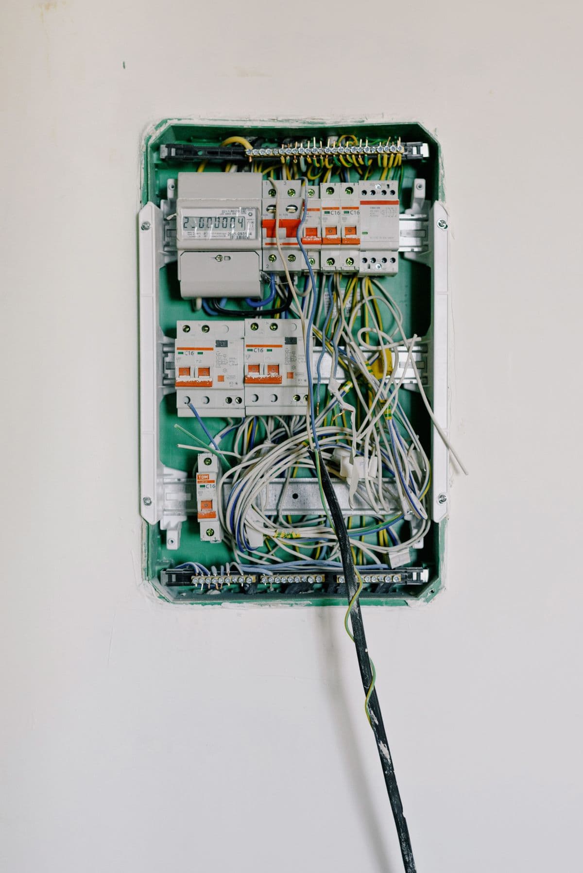 Tableau électrique résidentiel ouvert : disjoncteurs, bornier et câblage.