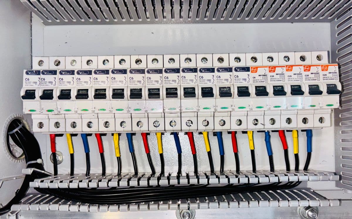 Rangée de disjoncteurs modulaires sur rail, câbles de couleur repérés.