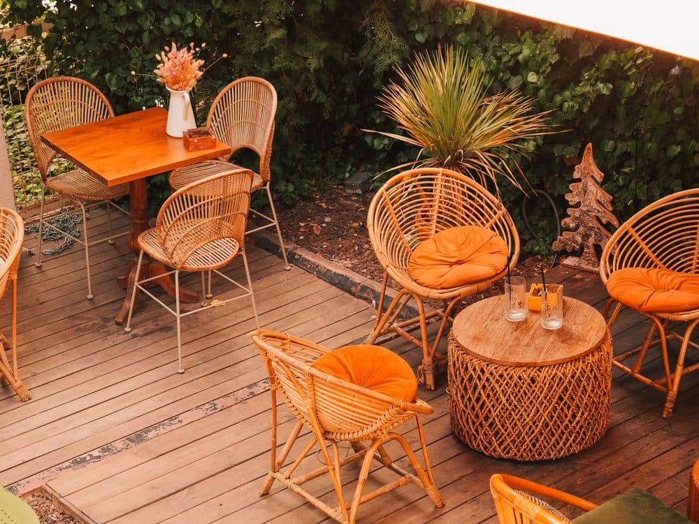 Terrasse aménagée sur platelage bois : fauteuils en rotin et jardinières, ambiance chaleureuse.