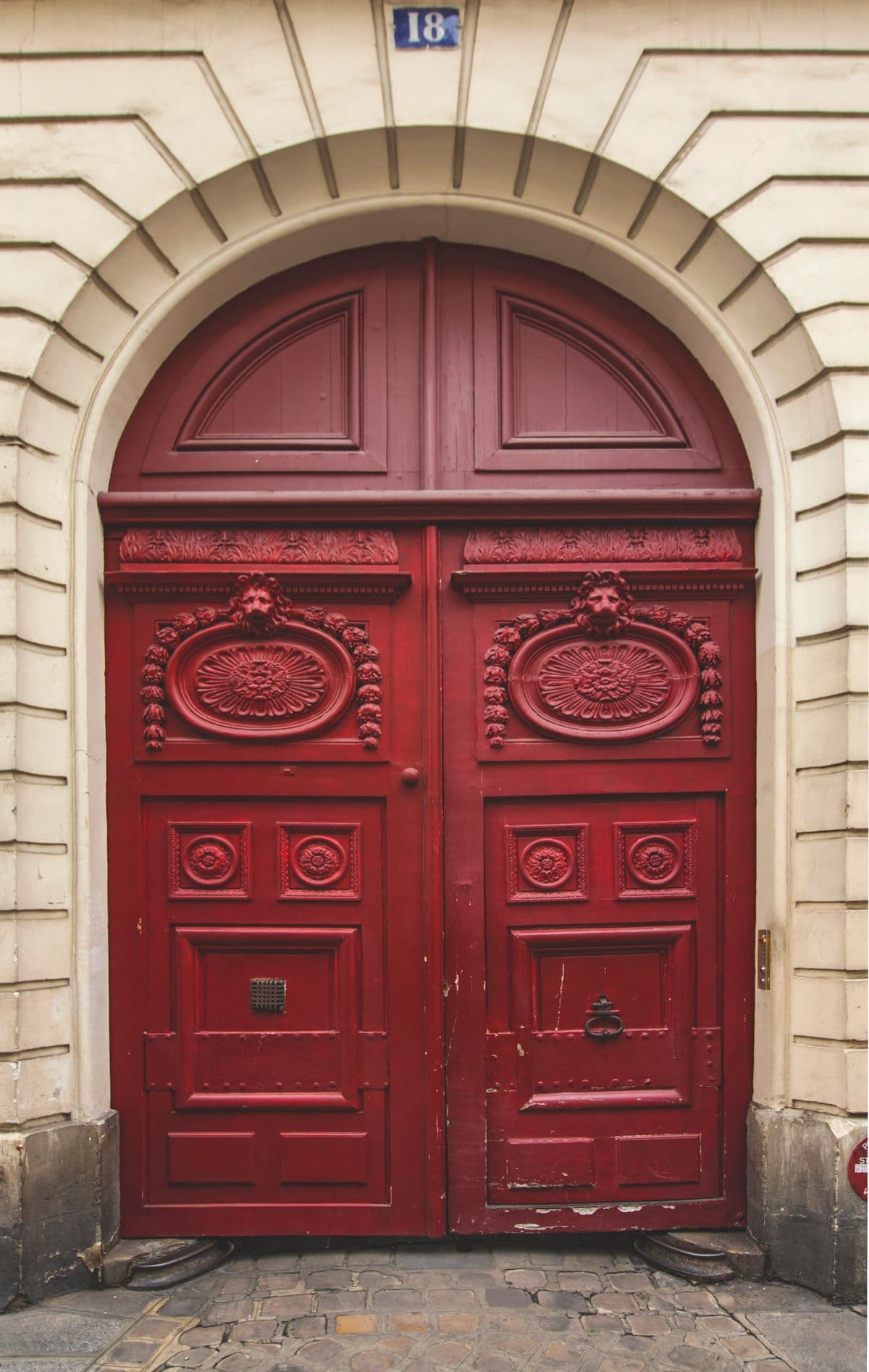 Grandes portes en bois ornées sous un porche, imposte et ferrures.