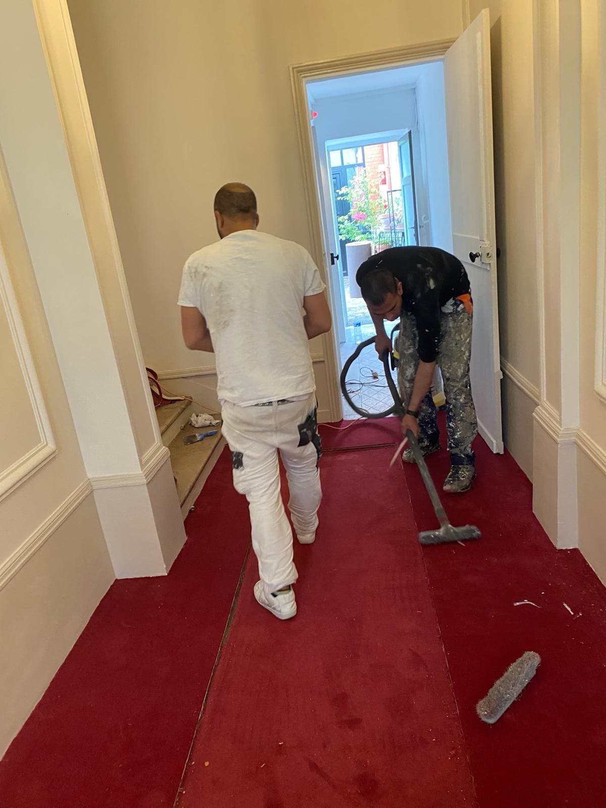 Peintre en intervention dans un couloir d'immeuble.