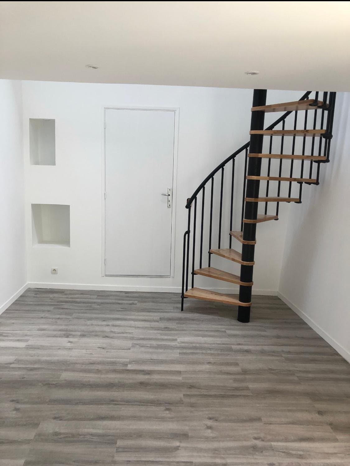 Séjour rénové, escalier et sol en parquet clair.