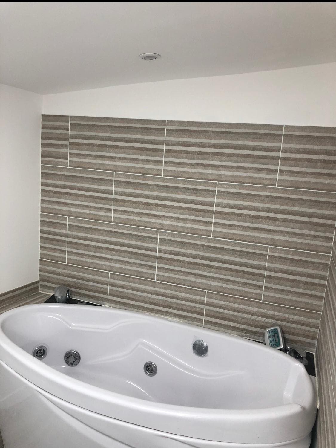 Salle de bains avec baignoire d'angle et carrelage.