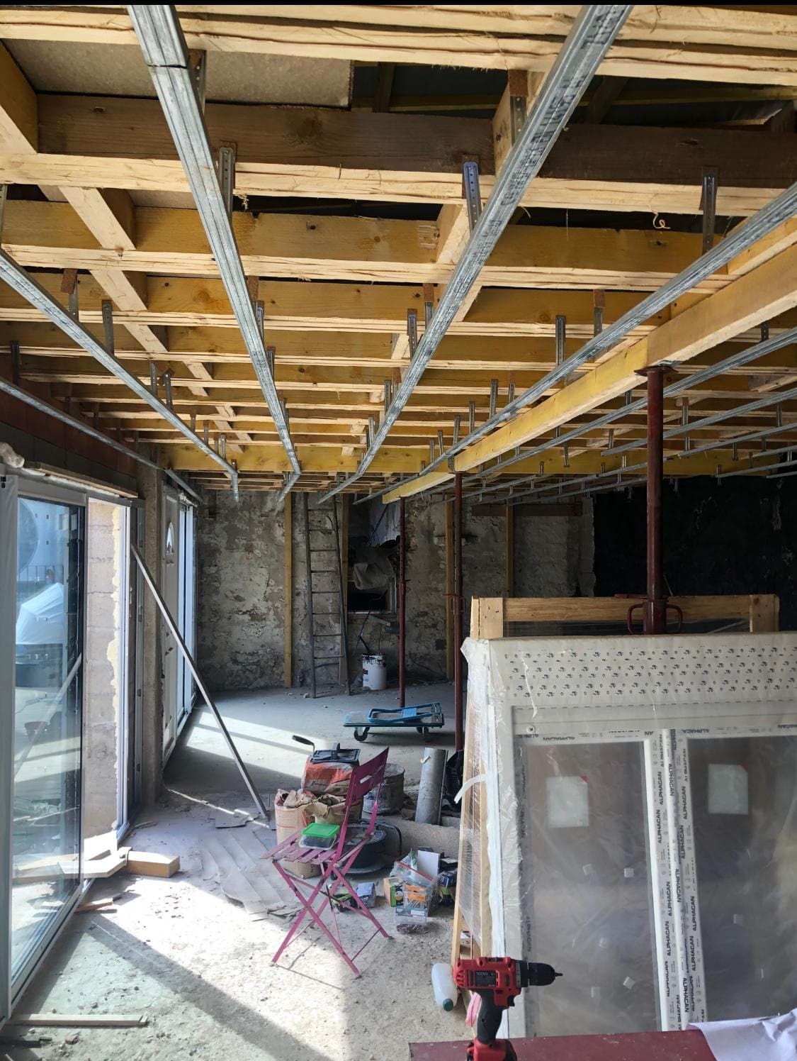 Rénovation intérieure en cours, charpente et baie ouverte.