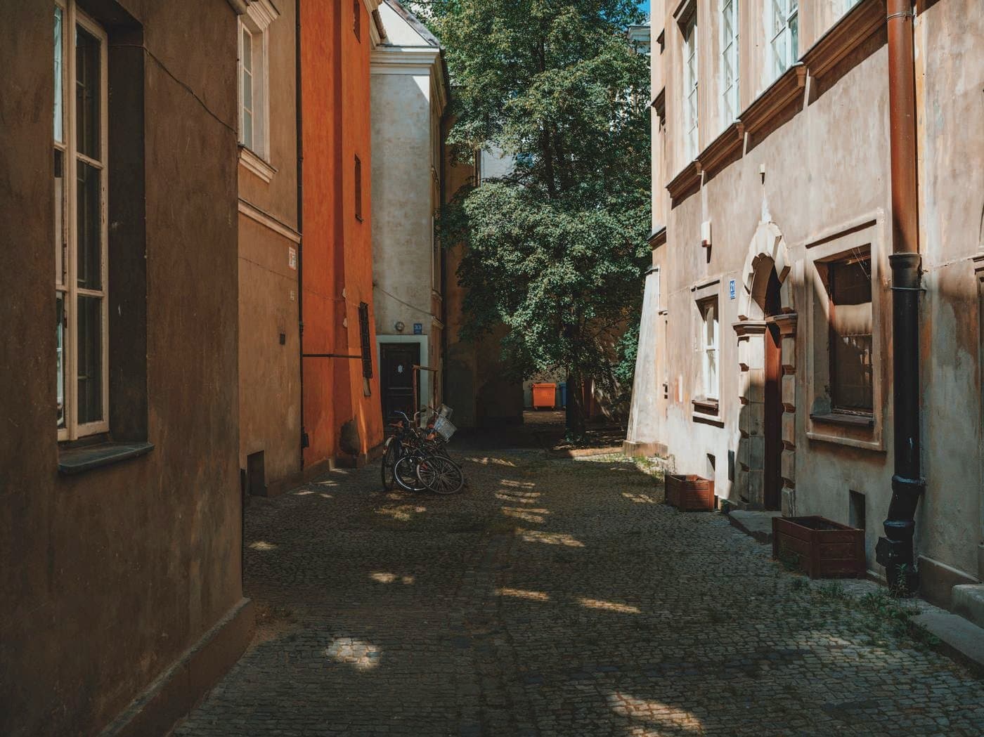 Ruelle pavée d'une vieille ville : calade de pavés au sol baignée d'une lumière rasante entre des façades chaudes.