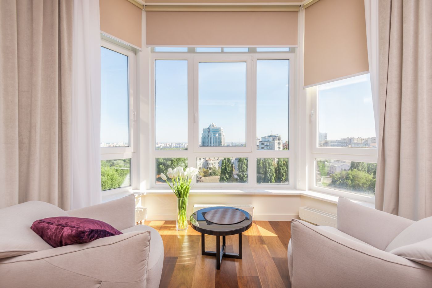 Baie vitrée d'un séjour rénové : grandes fenêtres ouvertes sur l'extérieur, tons chauds et mobilier clair.