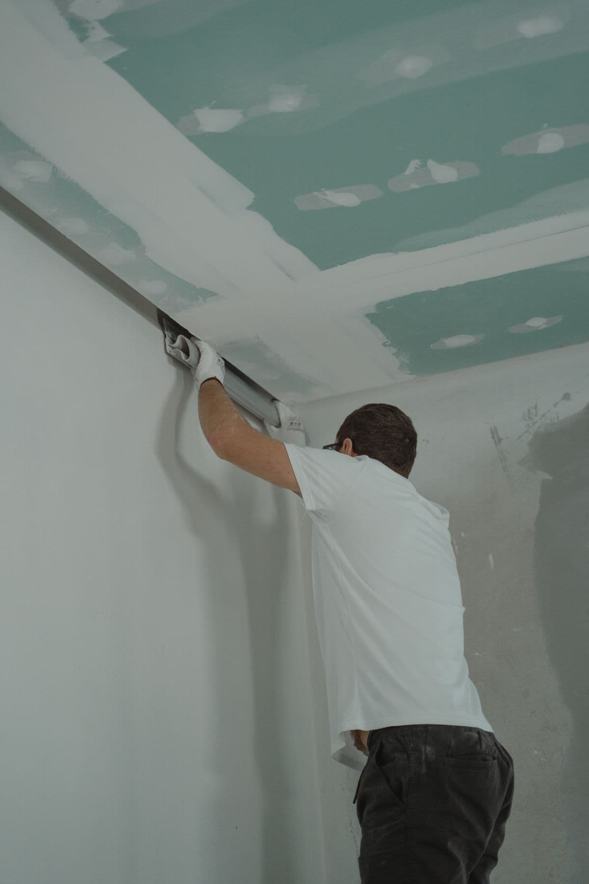 Pose d'une plaque de plâtre en plafond sur ossature métallique.