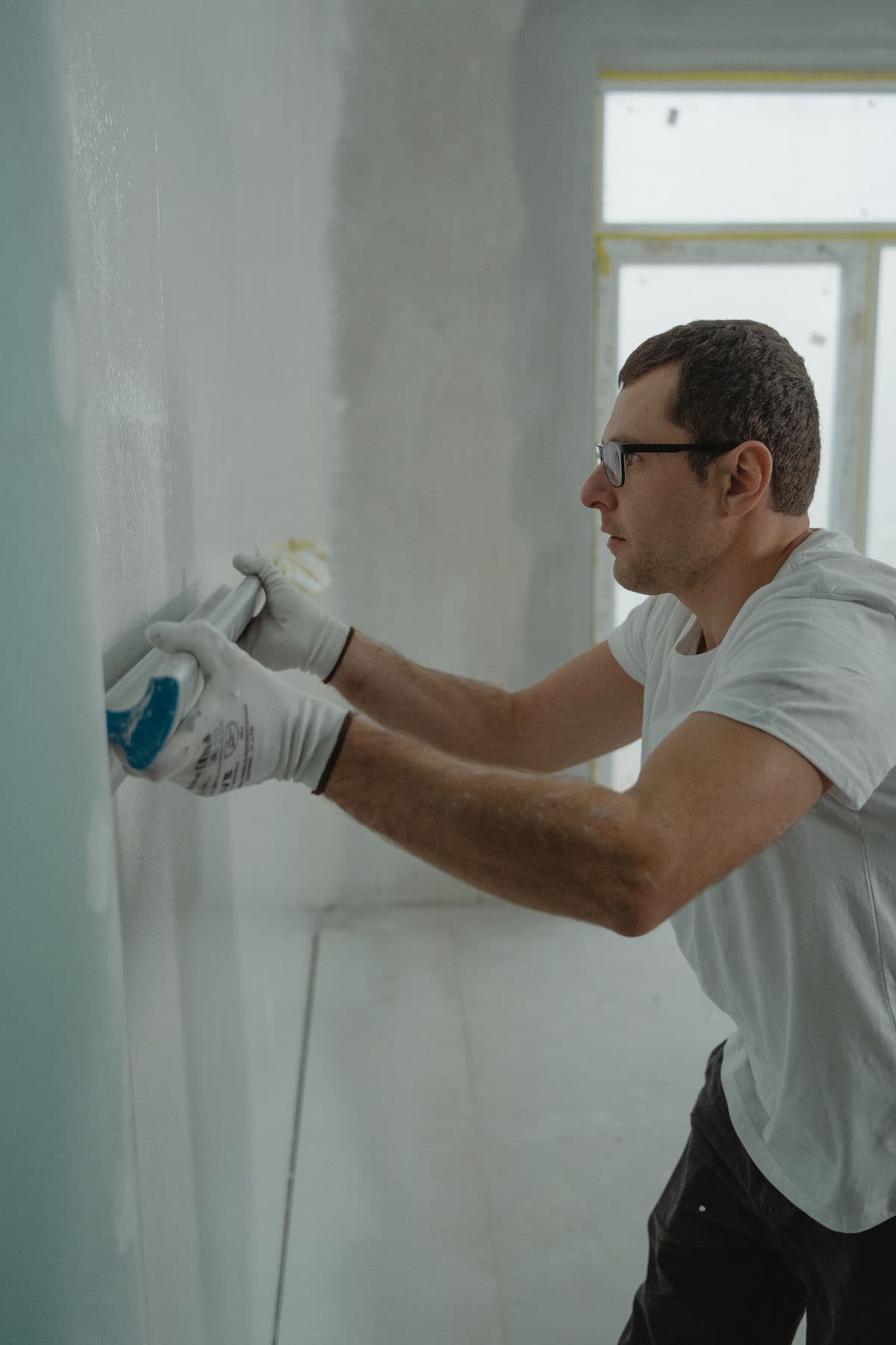 Application d'un enduit à la taloche sur un mur, en plâtrerie.