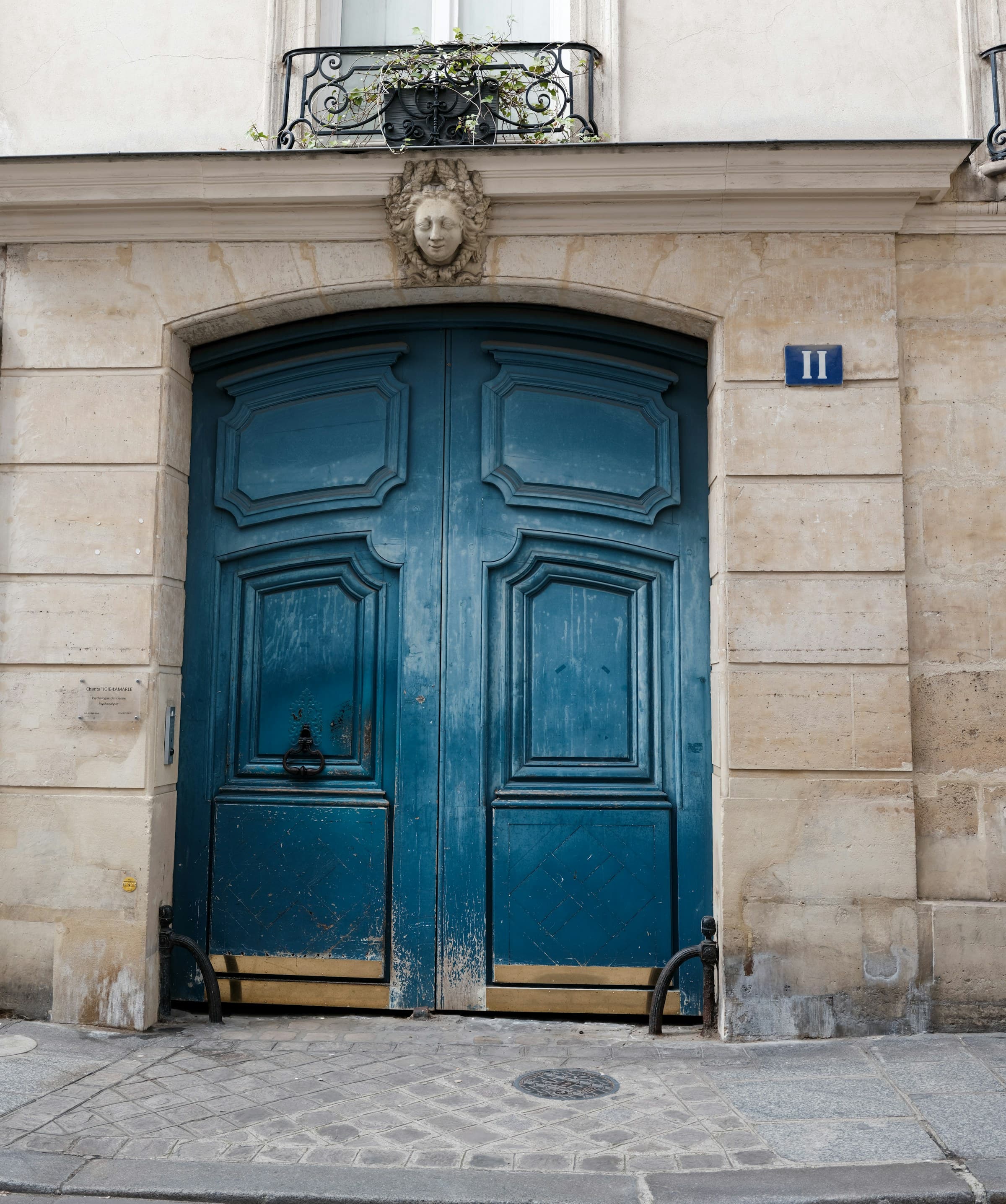 Porte cochère parisienne à deux vantaux en chêne, encadrée d'un chambranle en pierre de taille appareillée.